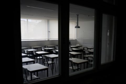 Leeres Klassenzimmer mit Tischen und Stühlen, Blick durch Fenster, Foto.