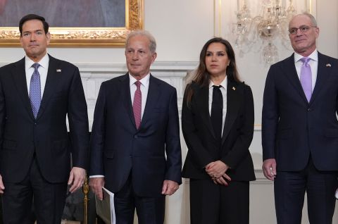 Vier Personen in Anzug und Kostüm stehen nebeneinander in elegantem Raum, Gruppenfoto, Foto.