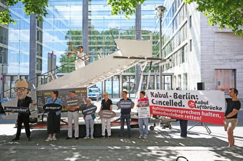 Aktivsten von Kabul Luftbrücke und Campact stehen während einer symbolischen Protestaktion am Weltflüchtlingstag zur Unterstützung mehrerer Klagen von Afghanen gegen die Bundesregierung vor dem Auswärtigen Amt. 