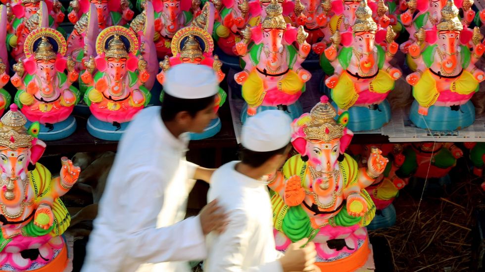 Indische Muslime laufen an hinduistischen Statuen vorbei.