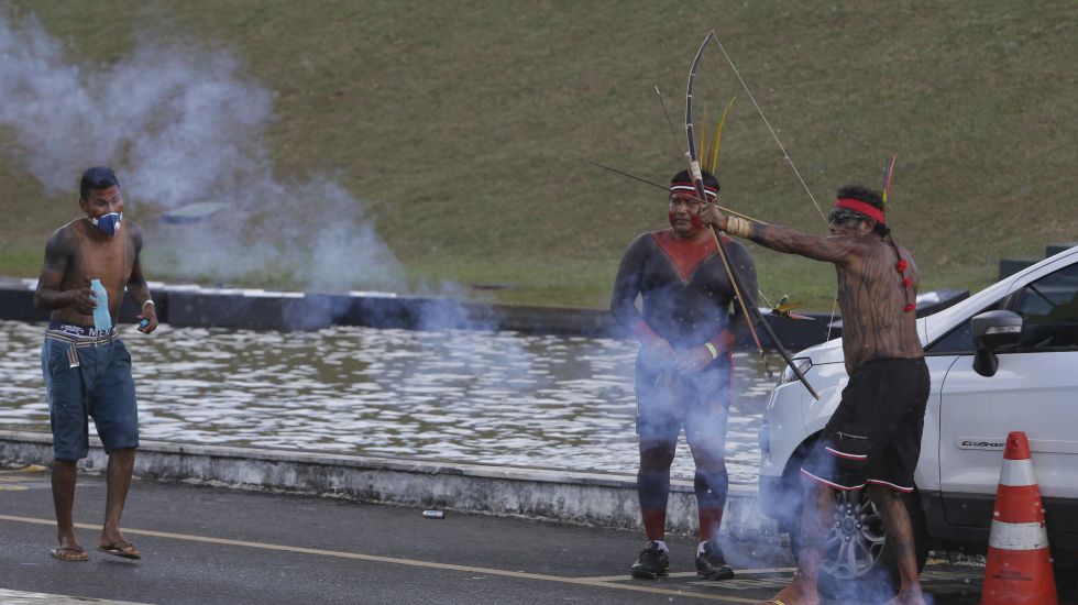 Inmitten von Tränengas, das von der Polizei eingesetzt wurde, spannt ein Indigener seinen Pfeil und Bogen