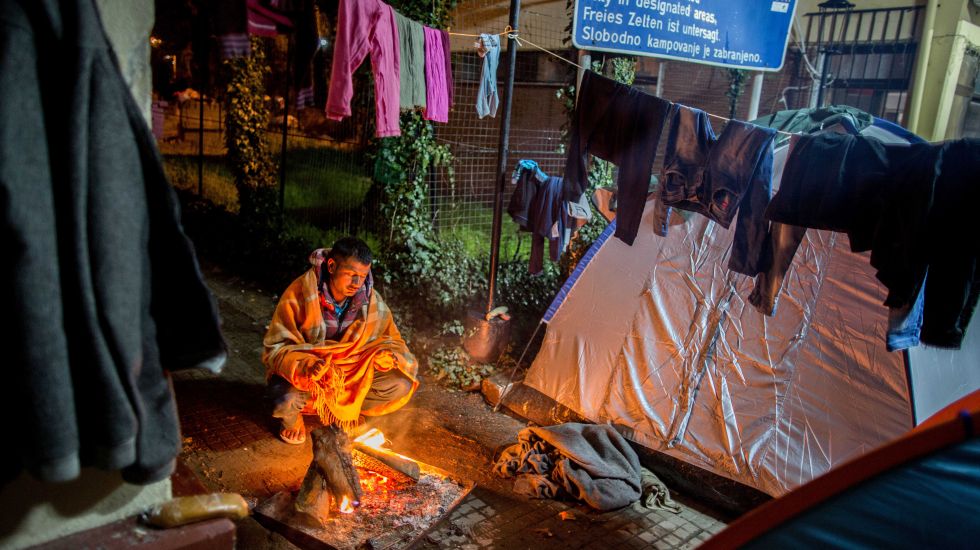 Ein Flüchtling sitzt am 13.03.2016 in Idomeni im Flüchtlingslager an der Grenze zwischen Griechenland und Mazedonien im Regen an einem Feuer.
