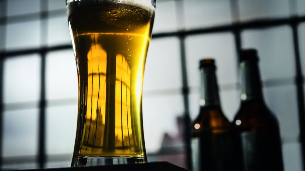 Nahaufnahme eines Glases Bier, im Hintergrund zwei Bierflaschen