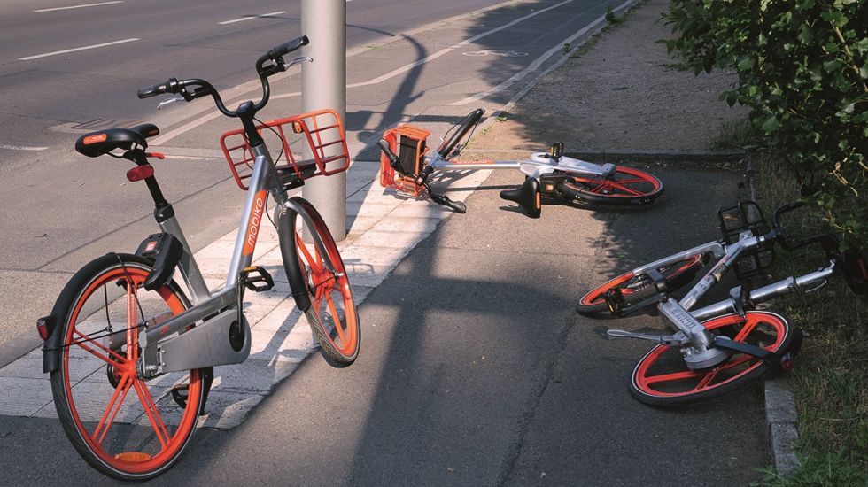 Bikesharing-Fahrräder liegen abgestellt auf einem Gehweg herum