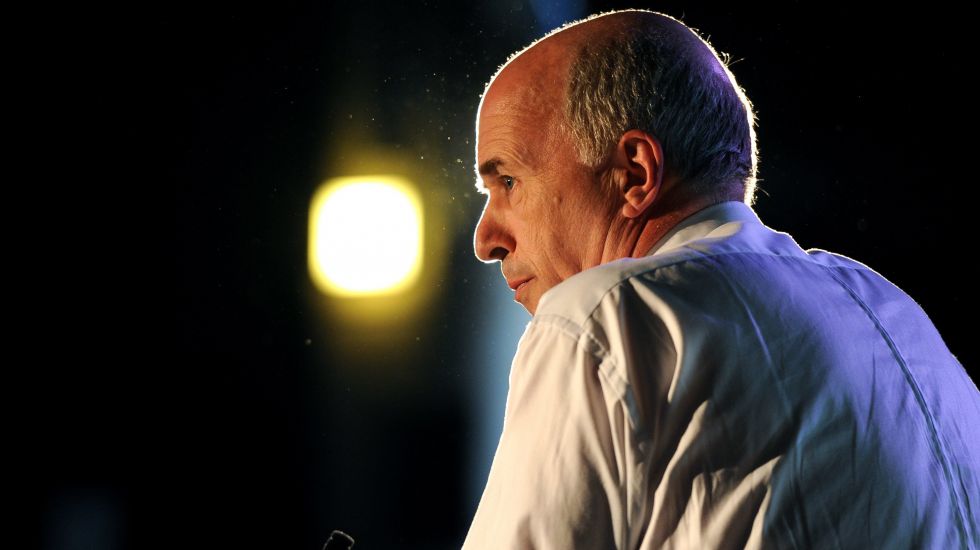 Carl-Peter Forster von der Seite fotografiert, am Podium vor einem Mikrofon stehend