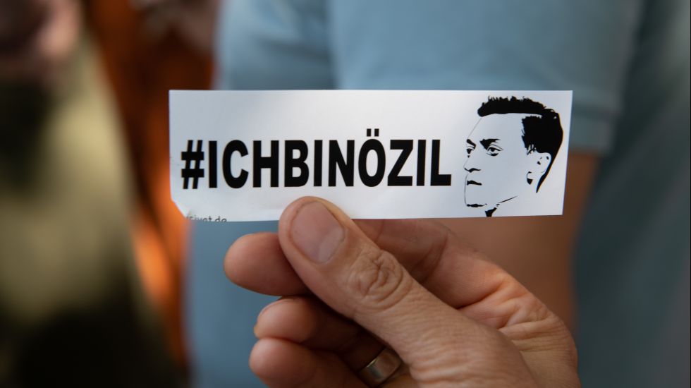 Ein Demonstrant zeigt bei einer Protestaktion vor dem Axel-Springer Hochhaus einen Aufkleber mit der Aufschrift "#Ichbinözil".