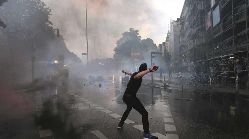 Vermummter Linksextremist wirft während des G20-Gipfels in der Hamburger Sternschanze einen Stein auf die anrückenden Polizisten