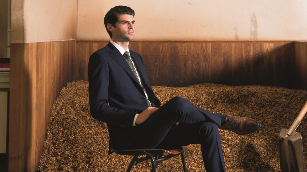 Nils Obermann sitzt in einem Anzug vor einer Ladung Tabak