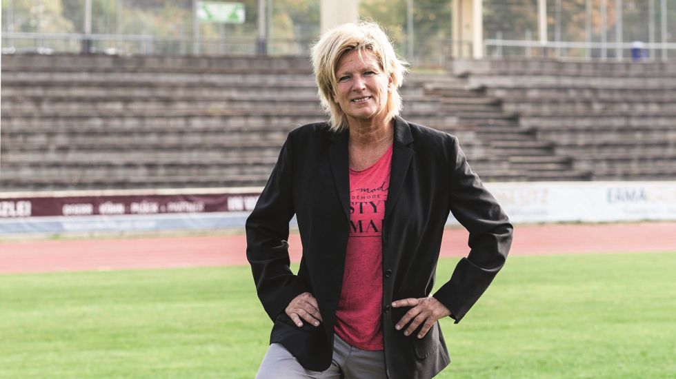 Claudia Neumann auf einem Fußballplatz, unter dem rechten Fuß ein Fußball