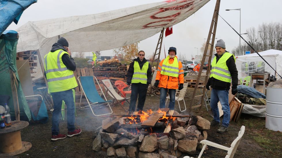  Vier "Gelbwesten" wärmen sich in ihrem Protestcamp nahe Straßburg an einem Lagerfeuer. 