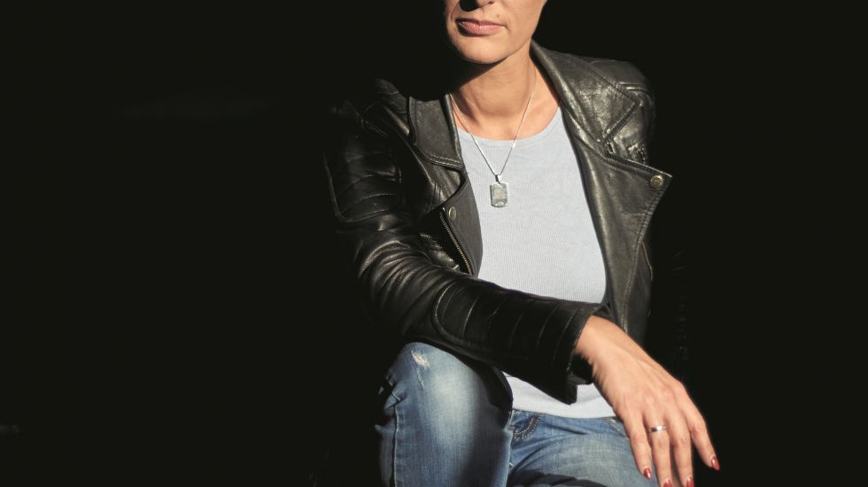 Dorotty Szalma sitzt vor schwarzem Hintergrund auf einer Treppe