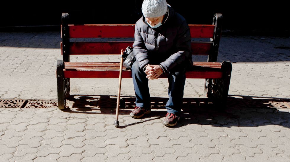 Ältere Frau sitzt auf Bank 