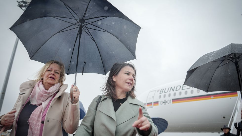 Nancy Faeser und Annalena Baerbock mit Regenschirm am Flughafen Tokio
