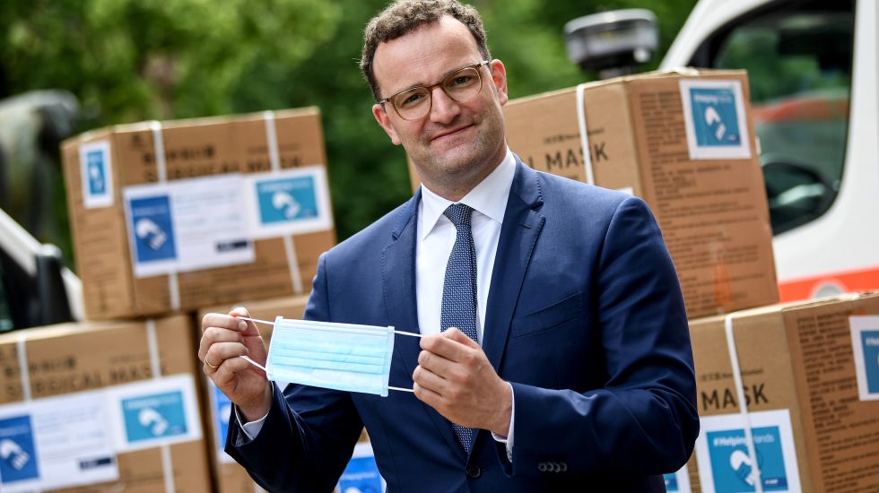Jens Spahn (CDU), Bundesgesundheitsminister, setzt sich bei der Übergabe der ersten Lieferung von 100 Millionen gespendeten Schutzmasken eine Maske auf.