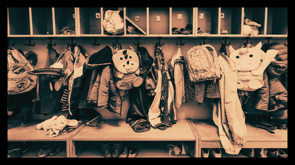 Foto: Garderobe mit vielen Kinderjacken, Rucksäcken und Mützen, keine Personen erkennbar.
