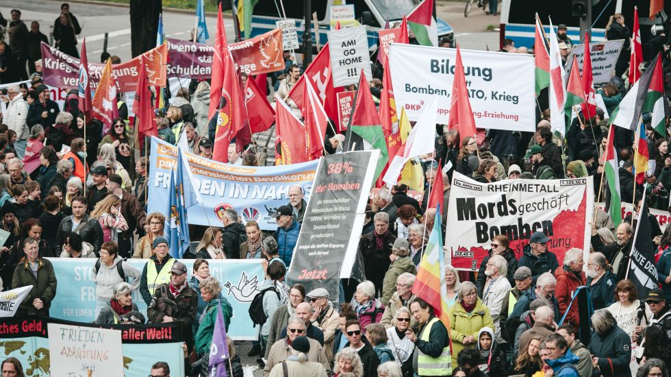 Große Menschenmenge bei einer Demonstration mit vielen bunten Fahnen und Bannern, Foto.