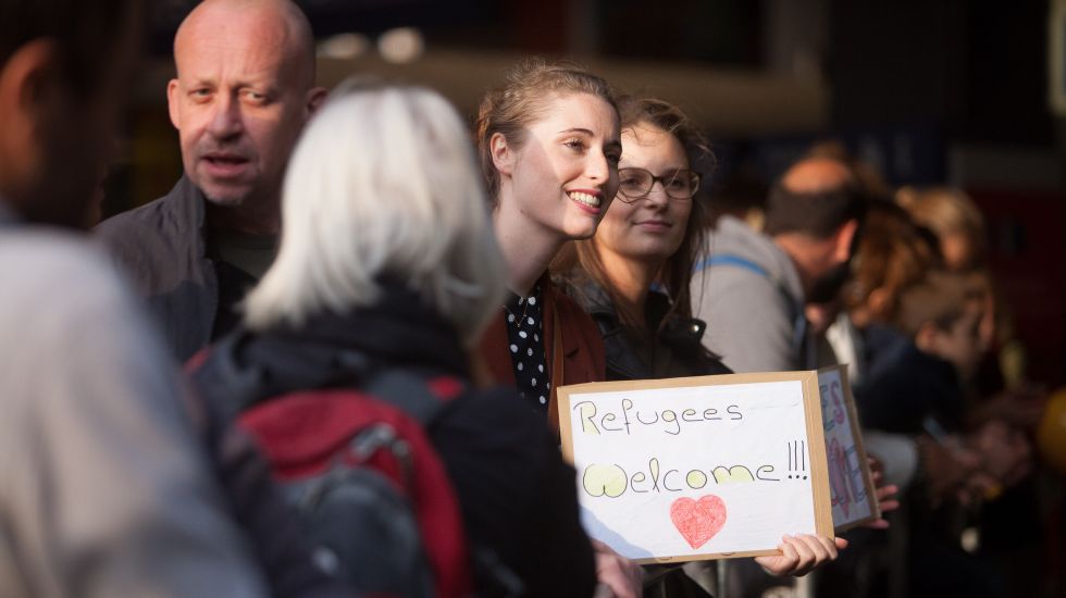 Mehrere Menschen stehen zusammen, eine Frau hält ein Schild, freundliche Atmosphäre, Foto.